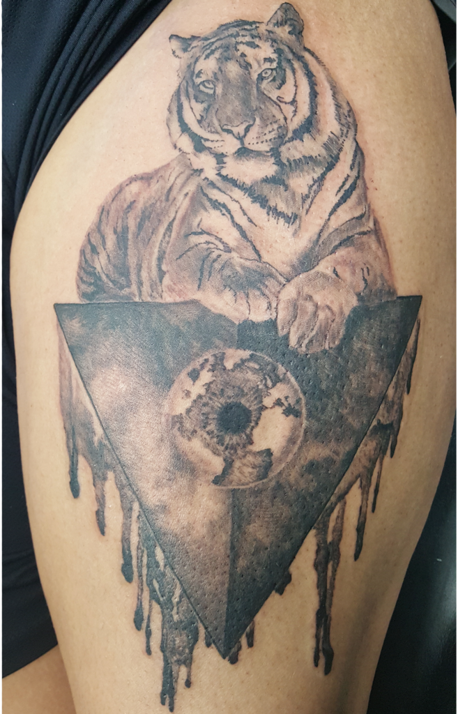 illuminati much?  Tiger resting on his hard won world conquest. Fun black and grey tattoo on a thigh.